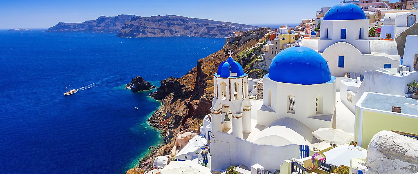 Ngôi nhà trắng mái vòm xanh tại Santorini, nổi bật trên vách đá với biển Aegean xanh biếc phía xa