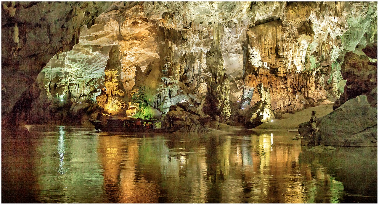 Những mảng màu sáng tối bên trong Động Phong Nha - Kẻ Bàng, với thạch nhũ lung linh phản chiếu trên dòng nước trong vắt lớn