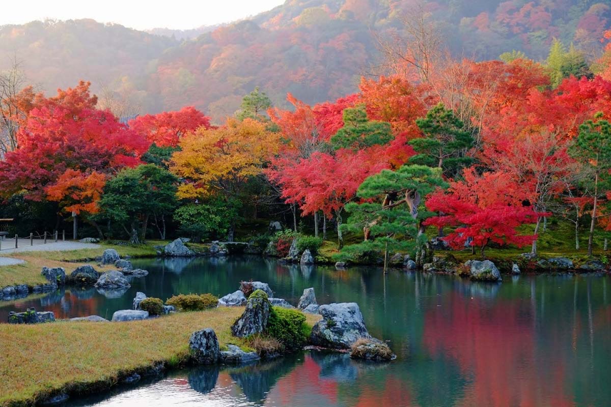 Vườn Zen chùa Tenryu-ji với lá phong đỏ phản chiếu trên mặt hồ yên bình